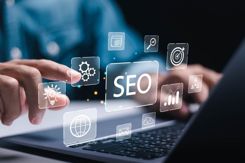 Ilustrasi konsep optimasi SEO website yang menampilkan grafik digital dan ikon pencarian di atas laptop.