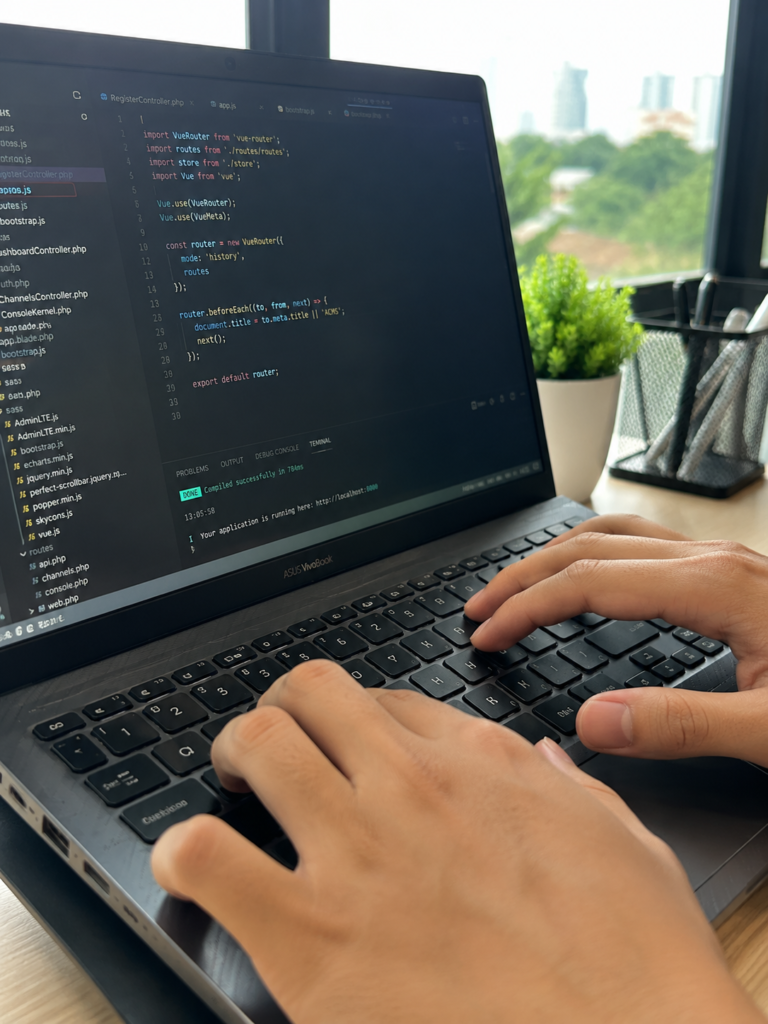 Seorang programmer sedang melakukan coding aplikasi mobile di laptop